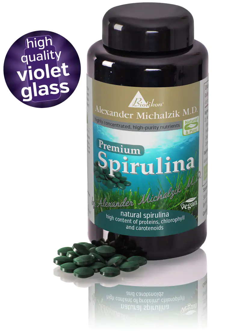 Premium Spirulina 1000 mg – Capsules Premium Spirulina in a violet glass container, 100 capsules, green tablets beside it.