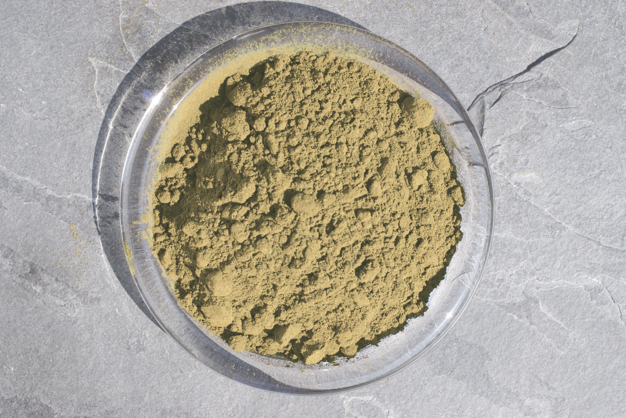 Herb Powder – 100 g Fine herb powder in a clear bowl, brown-greenish, viewed from above.